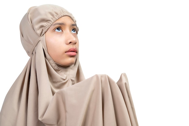 Ragazza musulmana asiatica in un hijab che alza le mani e prega
