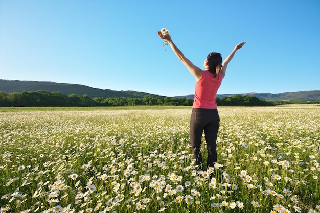 Ragazza nel campo di fiori di primavera a margherita