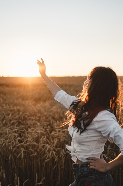 Ragazza nel campo di frumento al tramonto. Vita di vita lenta, concetto di salute mentale