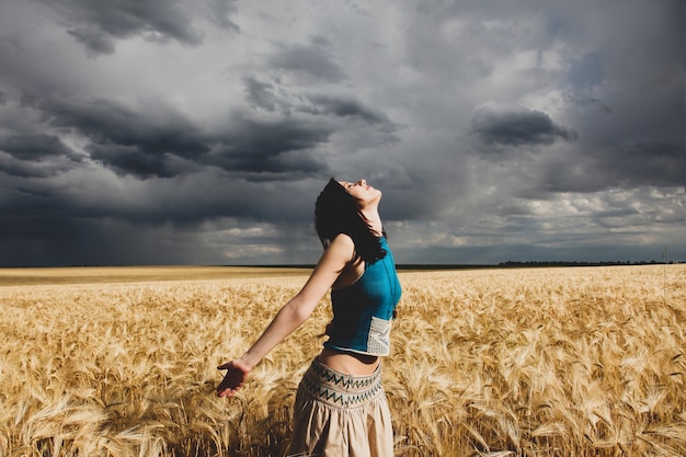 Ragazza nel campo di grano nel tempo di tempesta.