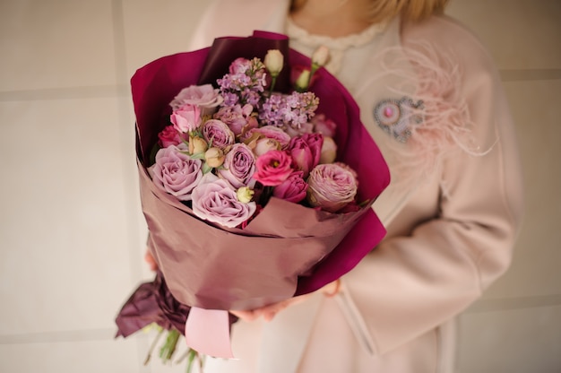 Ragazza nel cappotto che tiene un mazzo di fiori viola viola