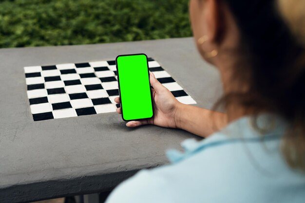 Ragazza nel parco con in mano uno smartphone con schermo verde Tavolo in cemento Chroma Key