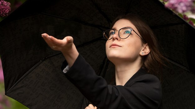 Ragazza nel parco durante la pioggia sotto l'ombrellone