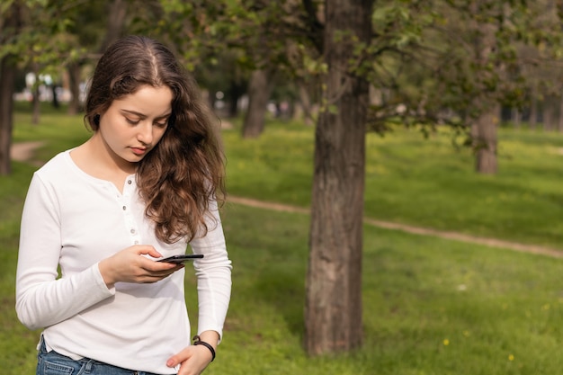 Ragazza nel parco utilizzando uno smartphone