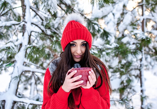 ragazza nella foresta invernale con una tazza di tè caldo