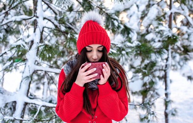 ragazza nella foresta invernale con una tazza di tè caldo