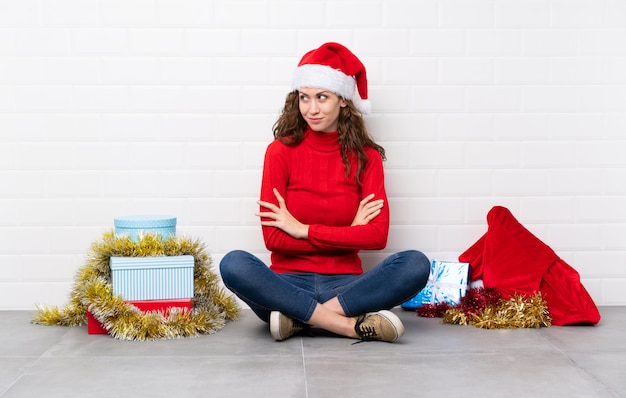 Ragazza nelle feste di natale che si siedono sul pavimento che pensa un'idea