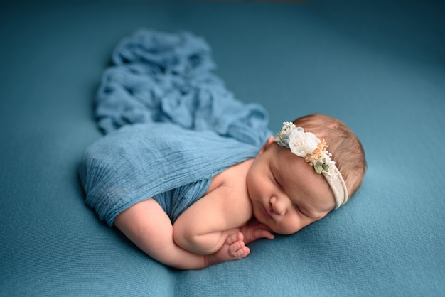 Ragazza neonata sveglia che dorme su una priorità bassa blu in uno spostamento blu.