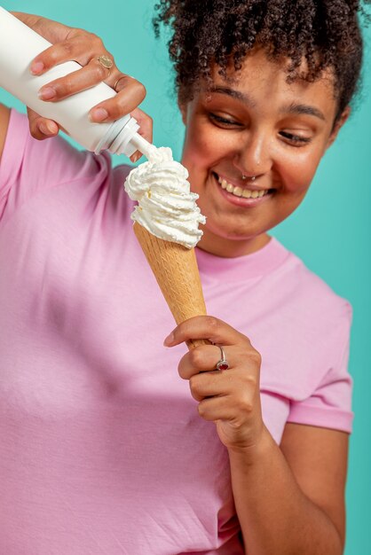 Ragazza nera che mangia un cono gelato su uno sfondo turchese