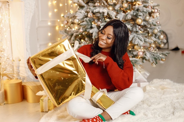 Ragazza nera vicino al regalo di apertura dell'albero di Natale a casa