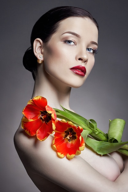 Ragazza nuda nuda con i fiori dei tulipani a disposizione