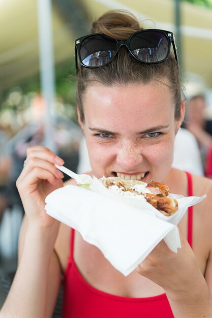 Ragazza o donna che mangia panino giroscopi. La ragazza con piacere mangia l'hamburger dopo la dieta.