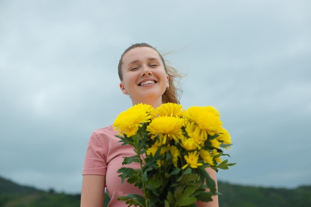 Ragazza ottenere fioritura mazzo di fiori occasione anniversario visita viaggio luna di miele all'aperto giovane donna dà un bouquet di fiori gialli all'esterno