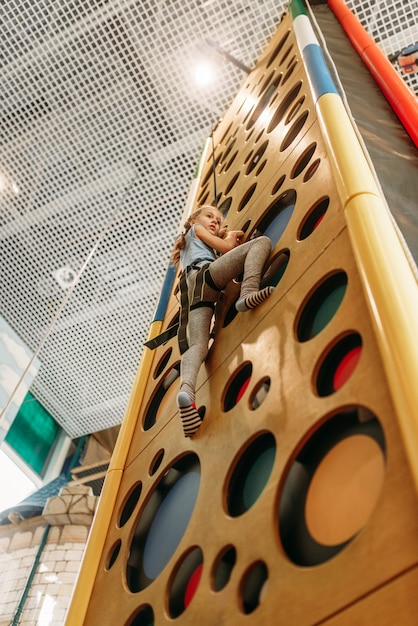 Ragazza pareti da arrampicata nel centro del gioco, vista dal basso