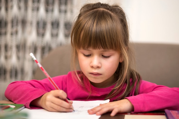 ragazza piccola bambina seria disegno con la matita su carta