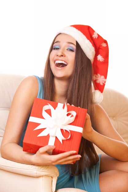 Ragazza positiva con il regalo in mano e nel cappello di Natale