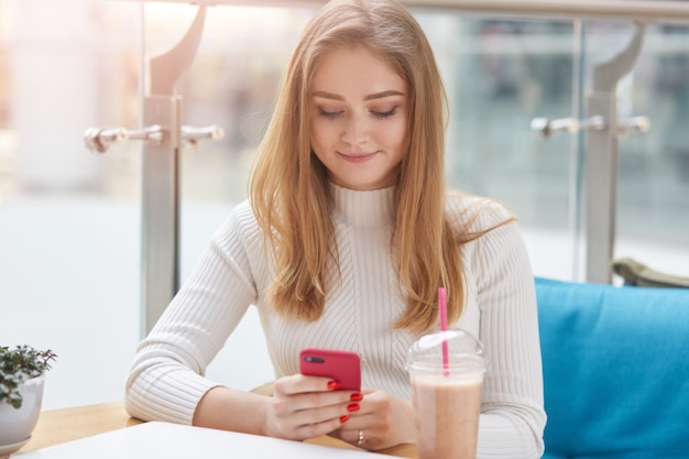 Ragazza positiva contentissima che tiene il suo smartphone rosso in mani