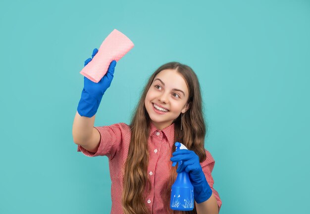 Ragazza positiva in guanti di gomma con flacone spray e straccio in microfibra su sfondo blu