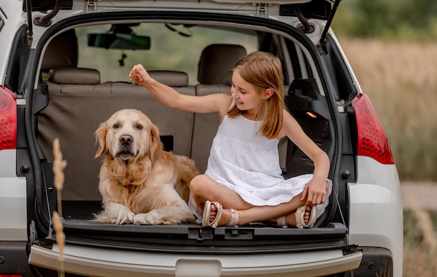 Ragazza preadolescente con cane golden retriever nel bagagliaio dell'auto