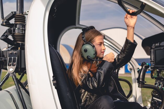 Ragazza preadolescente concentrata in cuffia pilota seduta nella cabina di pilotaggio dell'elicottero