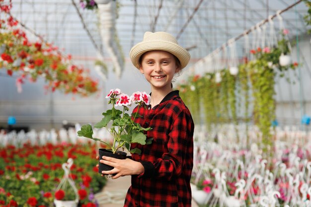 Ragazza preadolescente felice con un cappello e un vaso di fiori in mano bambino sorridente che guarda la telecamera è in