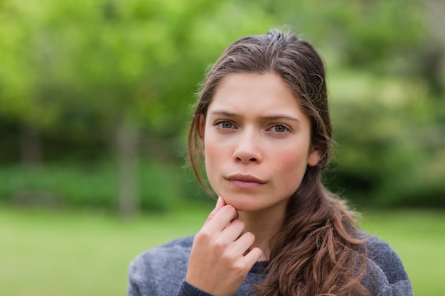 Ragazza premurosa che dispone la sua mano sul mento mentre stando in un parco