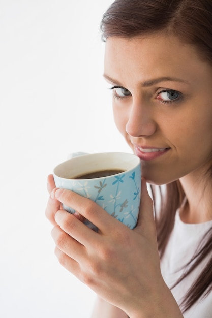 Ragazza premurosa che guarda l&#39;obbiettivo e bere una tazza di caffè