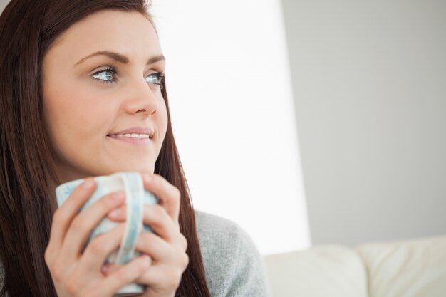 Ragazza premurosa che tiene una tazza di caffè e che osserva via