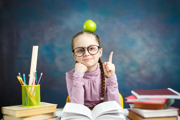 Ragazza premurosa della scuola elementare con la mela su aead che ha un'idea