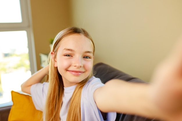 Ragazza preteen che fa foto selfie sul suo smartphone in un accogliente soggiorno a casa
