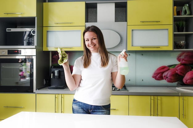 ragazza pulisce il tavolo della cucina con un detergente