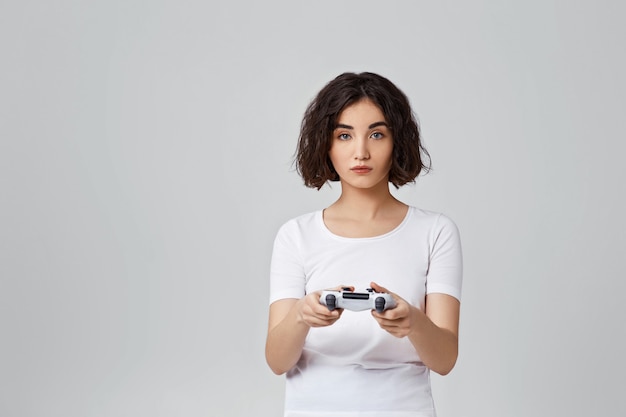 Ragazza riccia coinvolta che gioca ai videogiochi sulla console