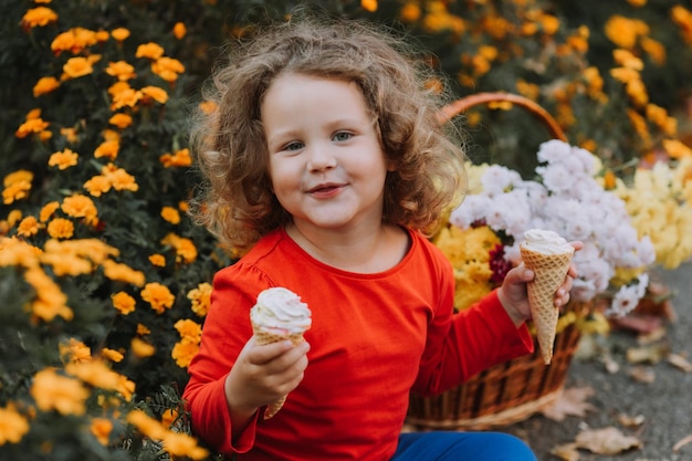 ragazza riccia sveglia che mangia il gelato nel parco fiorisce la carta di autunno di autunno banner