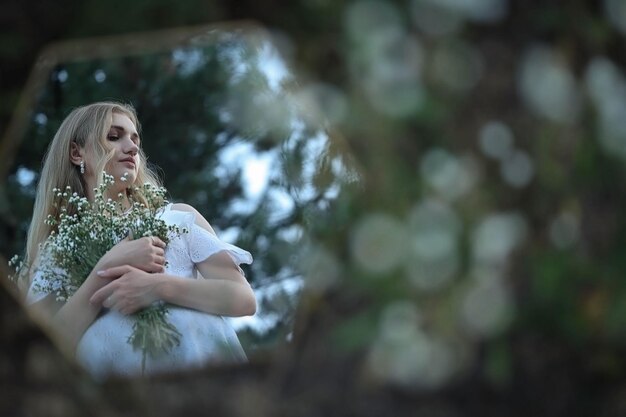 ragazza riflessa nello specchio con un mazzo di fiori di campo