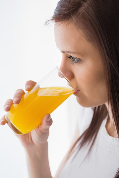 Ragazza rilassata che beve un bicchiere di succo d&#39;arancia