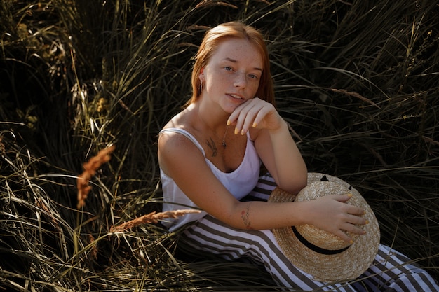 ragazza rossa con le lentiggini si siede nell'erba verde. ritratto estivo