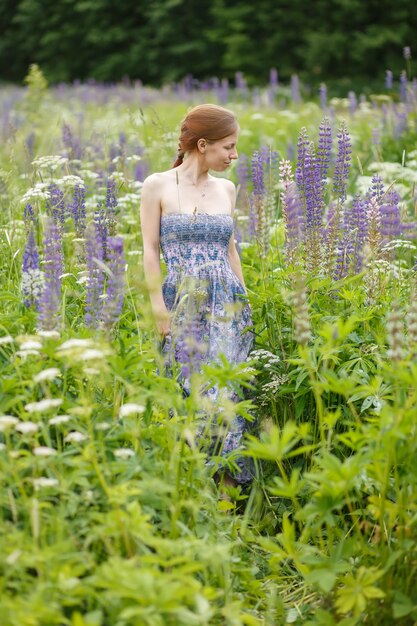 Ragazza rossa con lupini in fiore