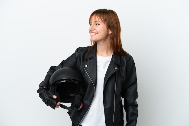 Ragazza rossa con un casco da motociclista isolato su sfondo bianco guardando il lato