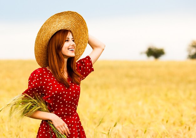 Ragazza rossa in vestito rosso al campo di grano