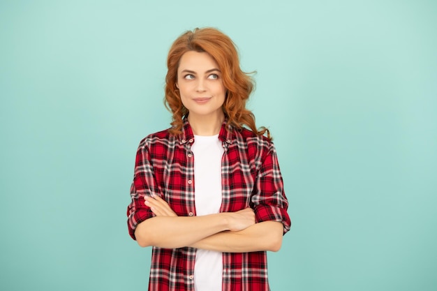 Ragazza rossa pensierosa in camicia a scacchi su sfondo blu