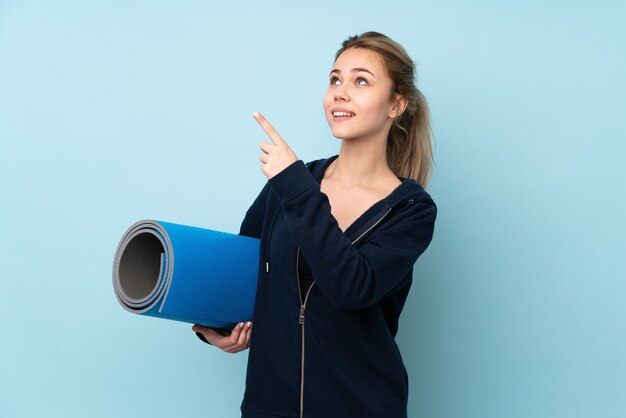 Ragazza russa dell'adolescente che tiene la stuoia isolata sul puntamento blu con il dito indice una grande idea