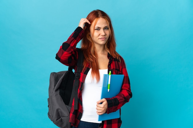 Ragazza russa dell'allievo dell'adolescente isolata su priorità bassa blu che ha dubbi