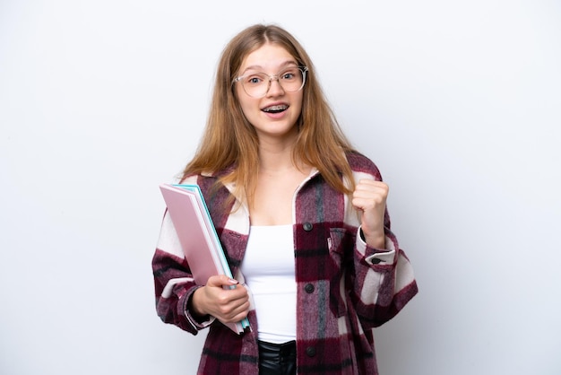 Ragazza russa dello studente dell'adolescente isolata su fondo bianco che celebra una vittoria nella posizione del vincitore