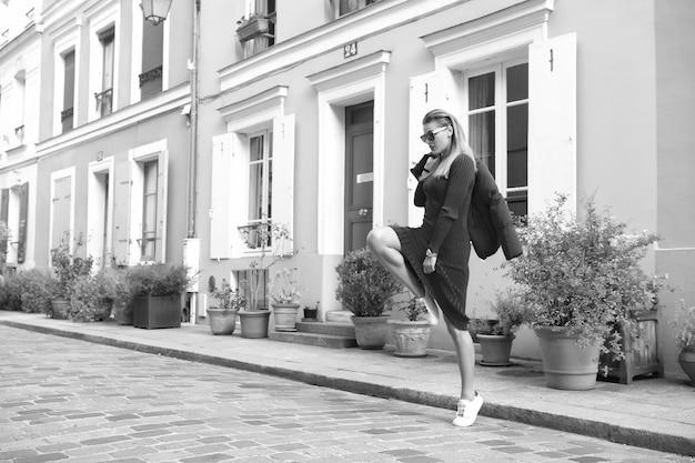 Ragazza salta in strada a Parigi Francia Donna con occhiali da sole in scarpe da ginnastica rosse a casa Moda concetto di stile autunnale Vacanza stile di vita viaggiare