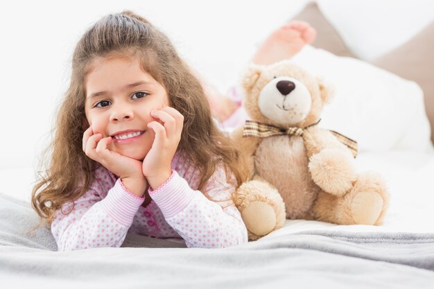 Ragazza sdraiata sul letto con orsacchiotto