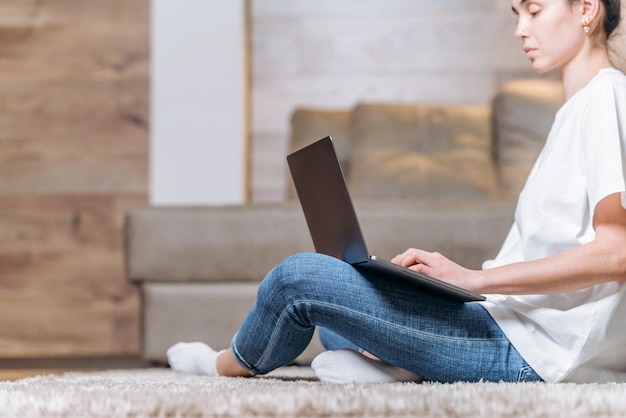 Ragazza seduta a casa a lavorare e navigare online sul computer portatile