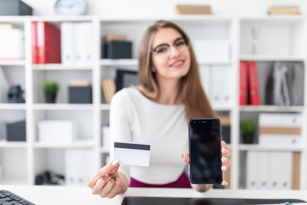 ragazza seduta a un tavolo e in possesso di un telefono e una carta di credito