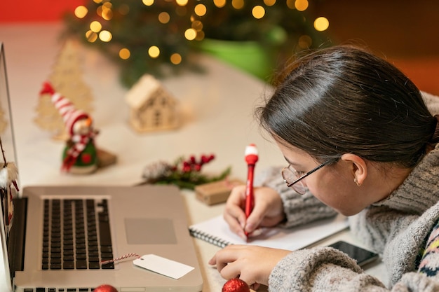 Ragazza seduta al laptop e scrivendo obiettivi il concetto di distanza sociale durante una pandemia