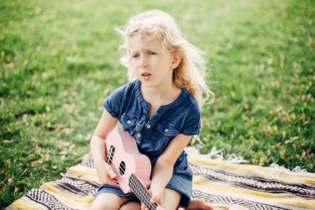 Ragazza seduta con uno strumento musicale sull'erba