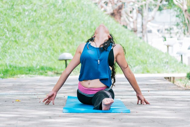 Ragazza seduta facendo yoga meditazione divisa all'aperto donna facendo yoga diviso laterale all'aperto giovane donna facendo yoga diviso laterale